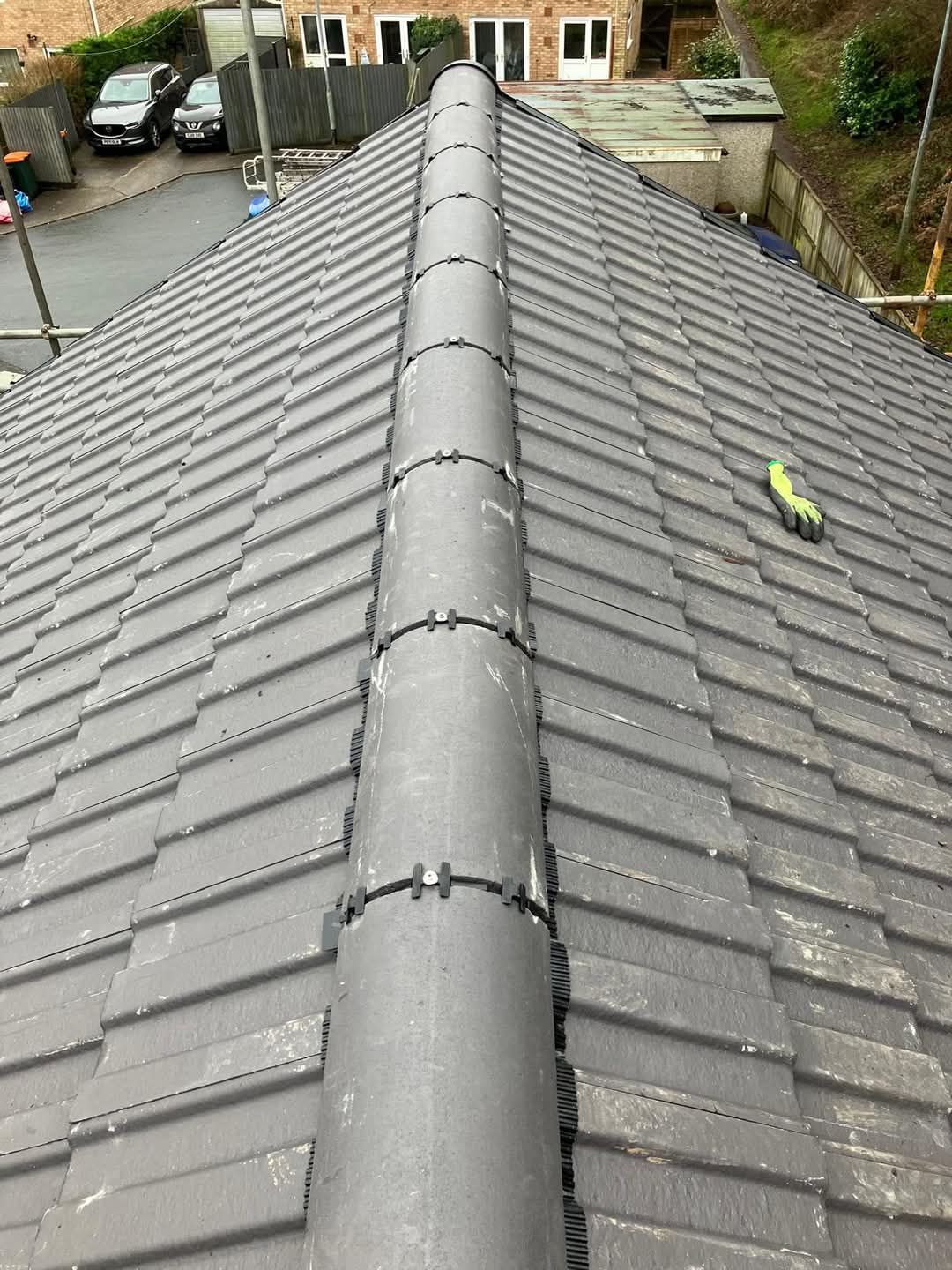 Completed grey tiled roof with mechanically fixed ridge tiles