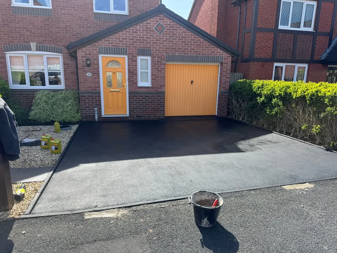 Freshly restored and sealed black tarmac driveway to a front of house